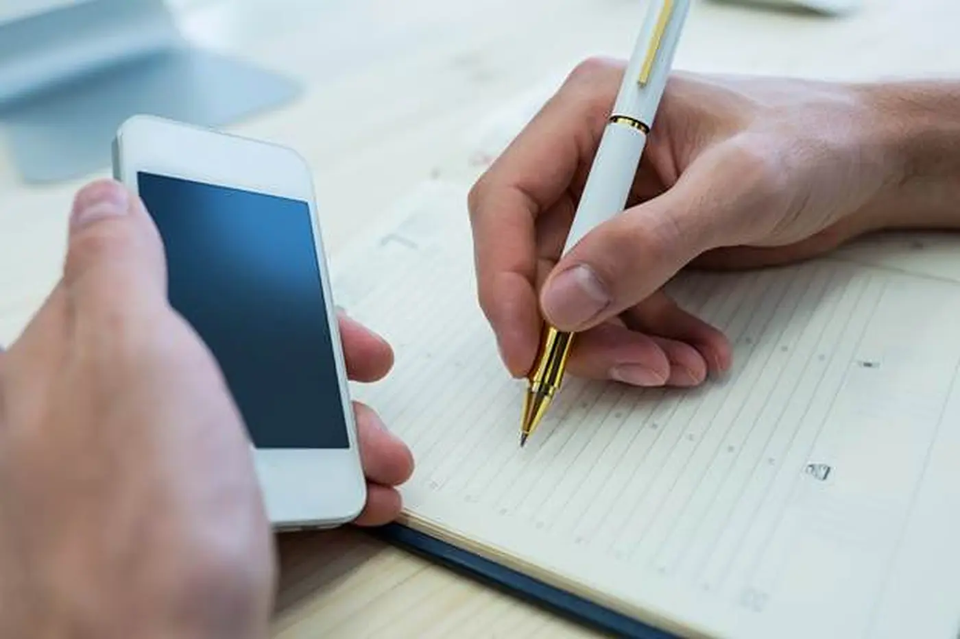 Writing an appointment in a planner beside a phone